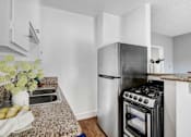 Thumbnail 9 of 19 - A kitchen with a black stove top oven and a white refrigerator.