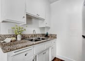 Thumbnail 10 of 19 - A kitchen with granite countertops and white cabinets.