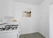 Thumbnail 11 of 26 - A white kitchen with a stove and cabinets.