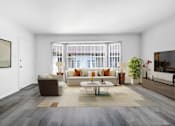 Thumbnail 3 of 26 - A living room with a brown and white sofa set, a coffee table, and a large painting on the wall.