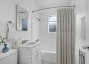 Thumbnail 9 of 26 - A white bathroom with a blue vase on the sink.