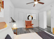 Thumbnail 8 of 26 - A bedroom with a bed, a chair, and a ceiling fan.