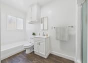 Thumbnail 7 of 32 - A white bathroom with a wooden floor and a window.