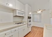 Thumbnail 1 of 14 - Kitchen with white gas cooktop over microwave, White Oven, Wood Style floors throughout dining area with ceiling fan