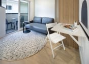 Thumbnail 9 of 16 - a small living room with a desk and a couch