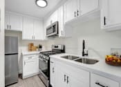 Thumbnail 1 of 83 - A modern kitchen with white cabinets and stainless steel appliances.