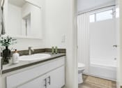 Thumbnail 5 of 95 - A white bathroom with a sink, mirror, toilet and bathtub.