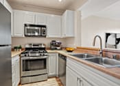 Thumbnail 10 of 26 - A modern kitchen with white cabinets and stainless steel appliances.