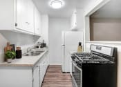 Thumbnail 6 of 28 - an empty kitchen with white cabinets and a stove and refrigerator