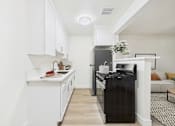 Thumbnail 29 of 55 - A black fridge sits in a white kitchen next to a white counter.