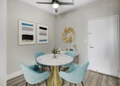 Thumbnail 14 of 26 - A dining room with a round table and blue chairs.