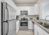 Thumbnail 12 of 26 - A modern kitchen with a refrigerator, stove, and microwave.