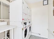 Thumbnail 11 of 15 - A white washing machine and dryer stacked on top of each other in a small room.