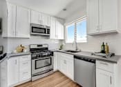 Thumbnail 11 of 28 - A kitchen with white cabinets and stainless steel appliances.