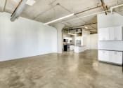 Thumbnail 29 of 92 - an empty room with white walls and concrete floors and a kitchen
