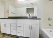 Thumbnail 36 of 92 - a bathroom with white cabinets and a sink and a mirror
