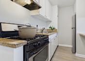 Thumbnail 12 of 65 - A kitchen with a black stove top and white cabinets.