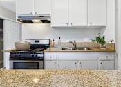 Thumbnail 11 of 65 - A kitchen with a black stove top oven and a granite counter top.