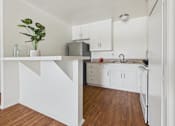 Thumbnail 5 of 46 - A kitchen with white cabinets and a wooden floor.