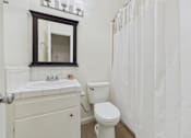 Thumbnail 27 of 46 - A white bathroom with a toilet, sink, and shower curtain.