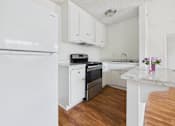 Thumbnail 28 of 46 - A kitchen with a white fridge, white cabinets, and a white counter.