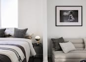 Thumbnail 26 of 46 - A black and white photo of a man is hanging on a wall above a grey couch at Skylar At Sunset Apartments, Los Angeles, CA, 90027