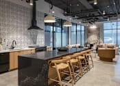 Thumbnail 2 of 46 - A modern kitchen with a black countertop and wooden chairs at Skylar At Sunset Apartments, Los Angeles, California