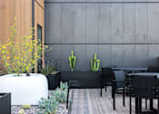 Thumbnail 19 of 46 - A modern outdoor dining area with a wooden table and chairs at Skylar At Sunset Apartments, Los Angeles, CA