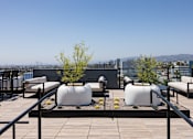Thumbnail 10 of 46 - A rooftop patio with white bean bag chairs and a black railing at Skylar At Sunset Apartments, Los Angeles, CA