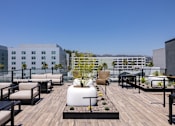 Thumbnail 11 of 46 - A rooftop patio with a wooden floor and furniture at Skylar At Sunset Apartments, Los Angeles, CA, 90027