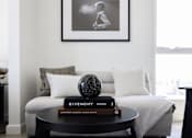 Thumbnail 35 of 46 - A living room with a white couch, a black coffee table, and a framed picture on the wall at Skylar At Sunset Apartments, Los Angeles 90027
