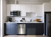 Thumbnail 29 of 46 - A modern kitchen with a stainless steel dishwasher and a black refrigerator at Skylar At Sunset Apartments, Los Angeles