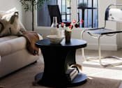 Thumbnail 33 of 46 - A black coffee table with a vase of flowers on it at Skylar At Sunset Apartments, Los Angeles, CA, 90027