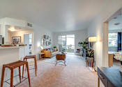 Thumbnail 47 of 53 - A living room with a kitchen area in the background.