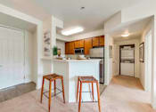 Thumbnail 46 of 53 - A kitchen with a white countertop and wooden stools.