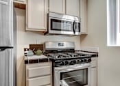 Thumbnail 1 of 16 - A modern kitchen with a stove, microwave, and refrigerator.
