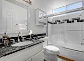 Thumbnail 10 of 16 - A white toilet sits in a bathroom with a marble counter top.