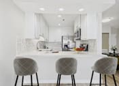 Thumbnail 1 of 77 - A modern kitchen with white cabinets and a white countertop.