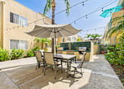Thumbnail 31 of 40 - A patio with a table and chairs under an umbrella.