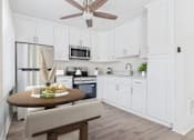 Thumbnail 23 of 81 - A kitchen with white cabinets and a wooden table.