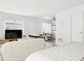 Thumbnail 26 of 81 - A white couch sits in a living room with a fireplace and a dining table in the background.