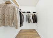 Thumbnail 28 of 81 - A row of clothes hangs on a rail in a white room.