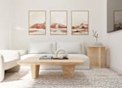 Thumbnail 9 of 163 - A living room with a white couch, a wooden coffee table, and three landscape paintings on the wall.