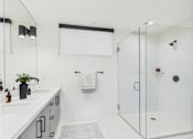 Thumbnail 13 of 157 - A white bathroom with a glass shower stall and a white sink.