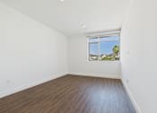 Thumbnail 44 of 45 - A room with a window overlooking a palm tree.
