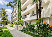Thumbnail 12 of 16 - A white apartment building with a green lawn in front.