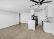 Thumbnail 77 of 95 - an empty living room with a kitchen and a ceiling fan
