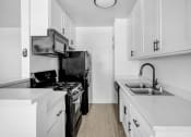 Thumbnail 25 of 95 - an all white kitchen with black appliances and white cabinets