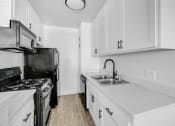 Thumbnail 24 of 95 - a kitchen with white cabinets and black appliances and a sink