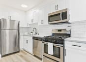 Thumbnail 24 of 66 - a white kitchen with stainless steel appliances and white cabinets